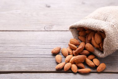 Gri ahşap arka plan üzerinde badem ile Çuval.