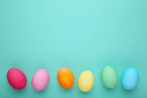 Colorful easter eggs on a mint background, flat lay