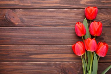 Kahverengi ahşap arka plan üzerinde kırmızı lale.