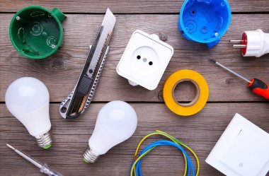 Gri ahşap arka plan üzerinde elektrikli alet seti. Mühendislik çalışmaları için aksesuarlar, enerji konsepti.