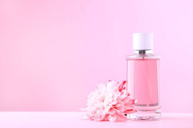 Pembe arka planda çiçekli parfüm şişesi
