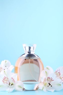 Mavi arka planda beyaz çiçeklerile parfüm şişesi