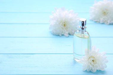 Mavi arka planda beyaz çiçeklerile parfüm şişesi