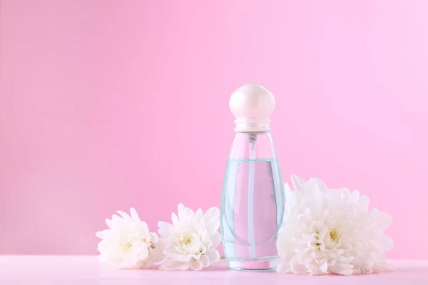 Flacon de parfum aux fleurs blanches sur fond rose — Photo