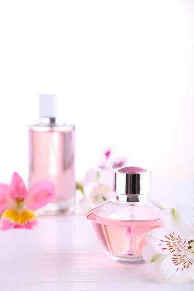 Parfümflaschen mit Blumen auf weißem Hintergrund, Draufsicht — Stockfoto