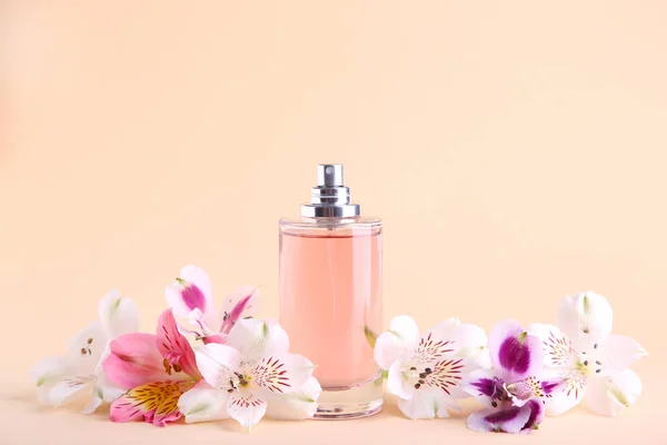 Bottle of perfume with flowers on beige background — Stock Photo, Image