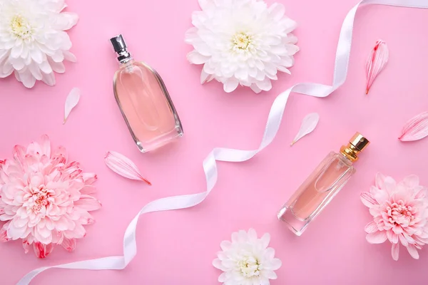 Frascos de perfume con flores sobre fondo rosa — Foto de Stock