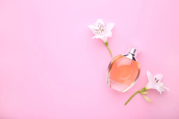 Láhev parfému s květinami na růžovém pozadí — Stock fotografie