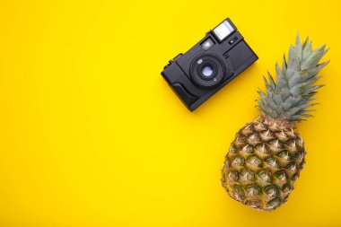 Sarı arka planda kamera ile Olgun ananas