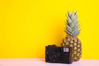Sarı arka planda kamera ile Olgun ananas