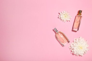 Çiçekli pembe bir arka plan üzerinde parfüm şişeleri