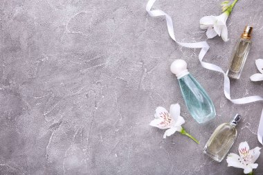 Gri beton arka plan üzerinde çiçek ile Parfüm şişeleri