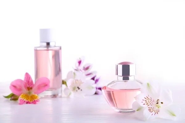 Perfume bottles with flowers on white background, top view — Stock Photo, Image