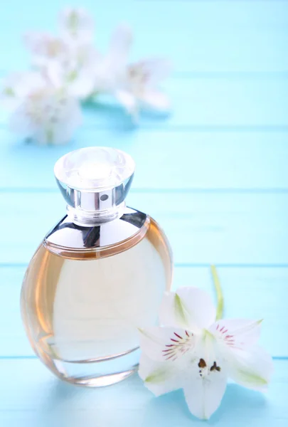 Fles parfum met witte bloemen op blauwe achtergrond — Stockfoto
