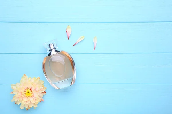 Garrafa de perfume com flores no fundo azul — Fotografia de Stock