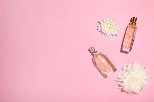 Frascos de perfume con flores sobre fondo rosa — Foto de Stock