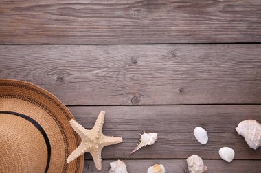 Gri ahşap masa üzerinde deniz kabukları ile Plaj şapkası