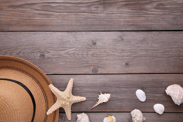 Beach hat with seashells on grey wooden table