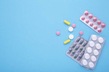 Mavi arka planda blister renkli haplar ve tabletler, üst görünüm
