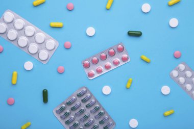 Mavi arka planda blister renkli haplar ve tabletler, üst görünüm