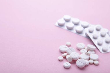 Beyaz haplar ve tabletler pembe arka plan üzerinde blister, üst görünümü