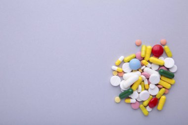 Gri arka planda renkli haplar ve tabletler, üst görünüm