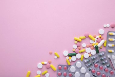Pembe arka planda blister renkli haplar ve tabletler, üst görünüm