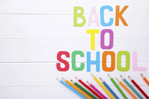 Inskription tillbaka till skolan med skolmaterial på vit trä bakgrund — Stockfoto