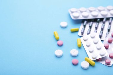 Mavi arka planda blister renkli haplar ve tabletler, üst görünüm