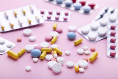 Pembe arka planda blister renkli haplar ve tabletler, üst görünüm