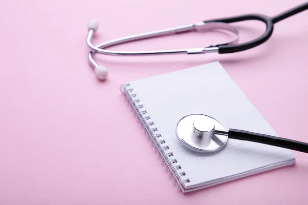 Stetoscopio con notebook su sfondo rosa. Vista dall'alto con posto per il testo . — Foto Stock