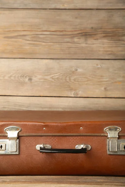 Old shabby leather portable suitcase for travel trip on brown background. Top view