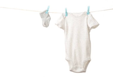 Çamaşır ipine asılı bebek kıyafetleri beyazda izole edilmiş. Üst görünüm