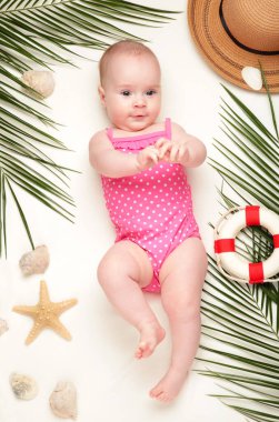 Plaj aksesuarları olan tatlı bir kız. Bebekle deniz tatili, yaz konsepti. Üst görünüm