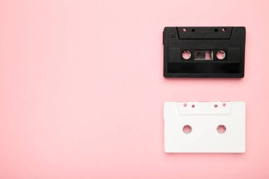 Pembe arka planda fotokopi alanı olan siyah beyaz ses kasetleri. Üst görünüm