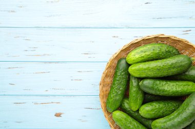 Mavi ahşap arka planda sepette taze salatalıklar. Üst görünüm