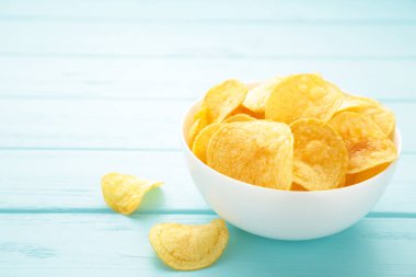 Patates cipsi kasede mavi ahşap arka planda. Üst görünüm