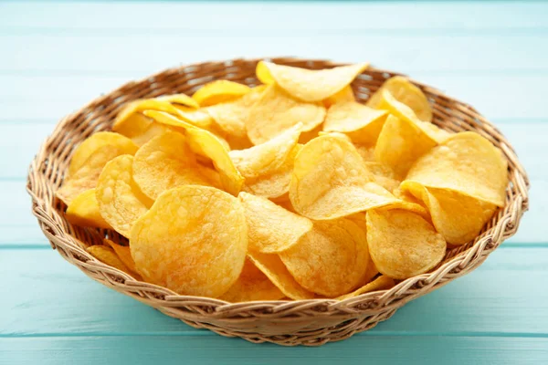 Mavi ahşap arka planda sepetin içinde altın patates cipsi. Üst görünüm