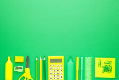 Yeşil arka planda okul malzemeleri. Okula dönelim. Düz yatıyordu. Üst görünüm