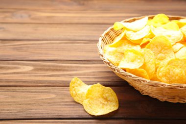 Kahverengi ahşap arka planda patates cipsi sepeti. Üst görünüm