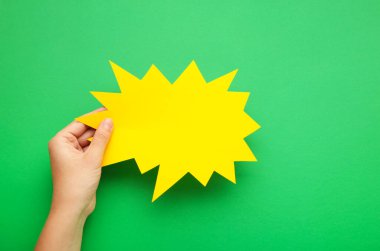 Yeşil arka planda sarı bir konuşma balonu tutuyor. Üst görünüm