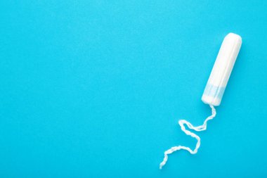 Mavi arka planda regl tamponu. Kadınlar için pamuk tampon. Üst görünüm