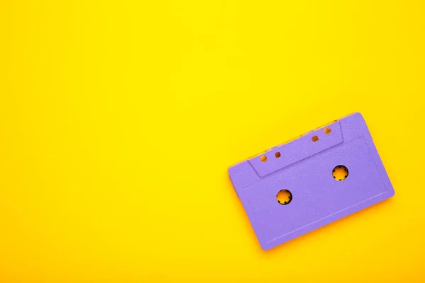 Old violet audio cassette on yellow background with copy space. Music day, top view