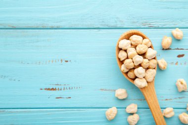 Mavi arka planda ahşap kaşıkta pişmemiş nohut.