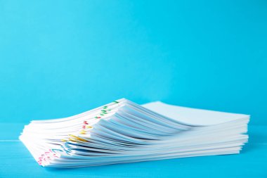 Mavi üzerine beyaz kağıt yığını doldurulmuş renkli ataç. Üst görünüm