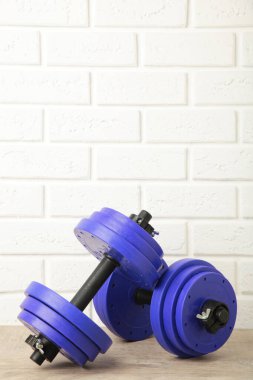 Beyaz tuğlalı duvara mor halterler. Spor konsepti.