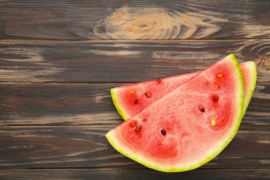 Kahverengi ahşap arka planda taze çizgili dilimlenmiş karpuz..