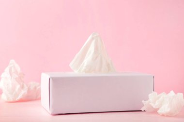 Kağıt mendilli kutu ve pembe arka planda buruşmuş peçete kullanılmış. Üst görünüm