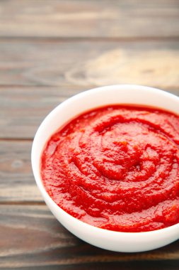 Kahverengi ahşap masada bir kase ketçap ya da domates sosu. Üst Manzara. Dikey