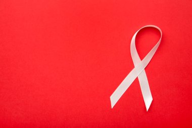 Kırmızı arka planda pembe saten göğüs kanseri farkındalığı kurdeleleri. Üst görünüm.